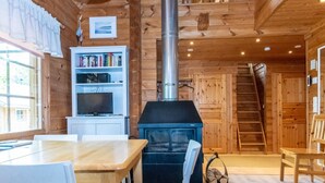 A cozy cabin interior with a wooden interior, a fireplace, a bookshelf, and a dining area.