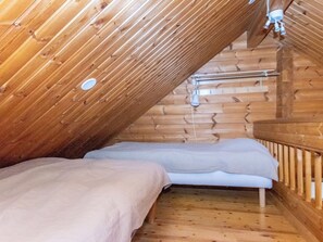A small, wooden cabin with a sloped ceiling, two beds, and a single light fixture. - Ressipysäkki 2 by Interhome (Inari)
