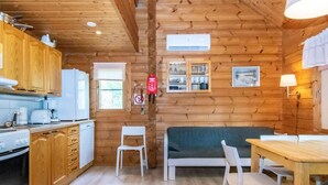A cozy cabin-style kitchen with wooden walls, a dining area, and a sofa.