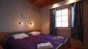Una habitación con una cama, dos lámparas de noche, una ventana con cortinas y un cuadro en la pared.