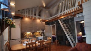 Una cocina amplia con armarios de madera, una mesa de comedor y sillas. Una escalera conduce a un nivel superior.