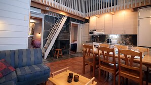 Un interior acogedor con comedor, cocina y una escalera que lleva a un nivel superior.