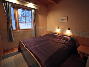 A bedroom with a bed, a window with curtains, a headboard with wall lights, and a framed picture on the wall. - Tunturikoivu b1 by Interhome (Inari)