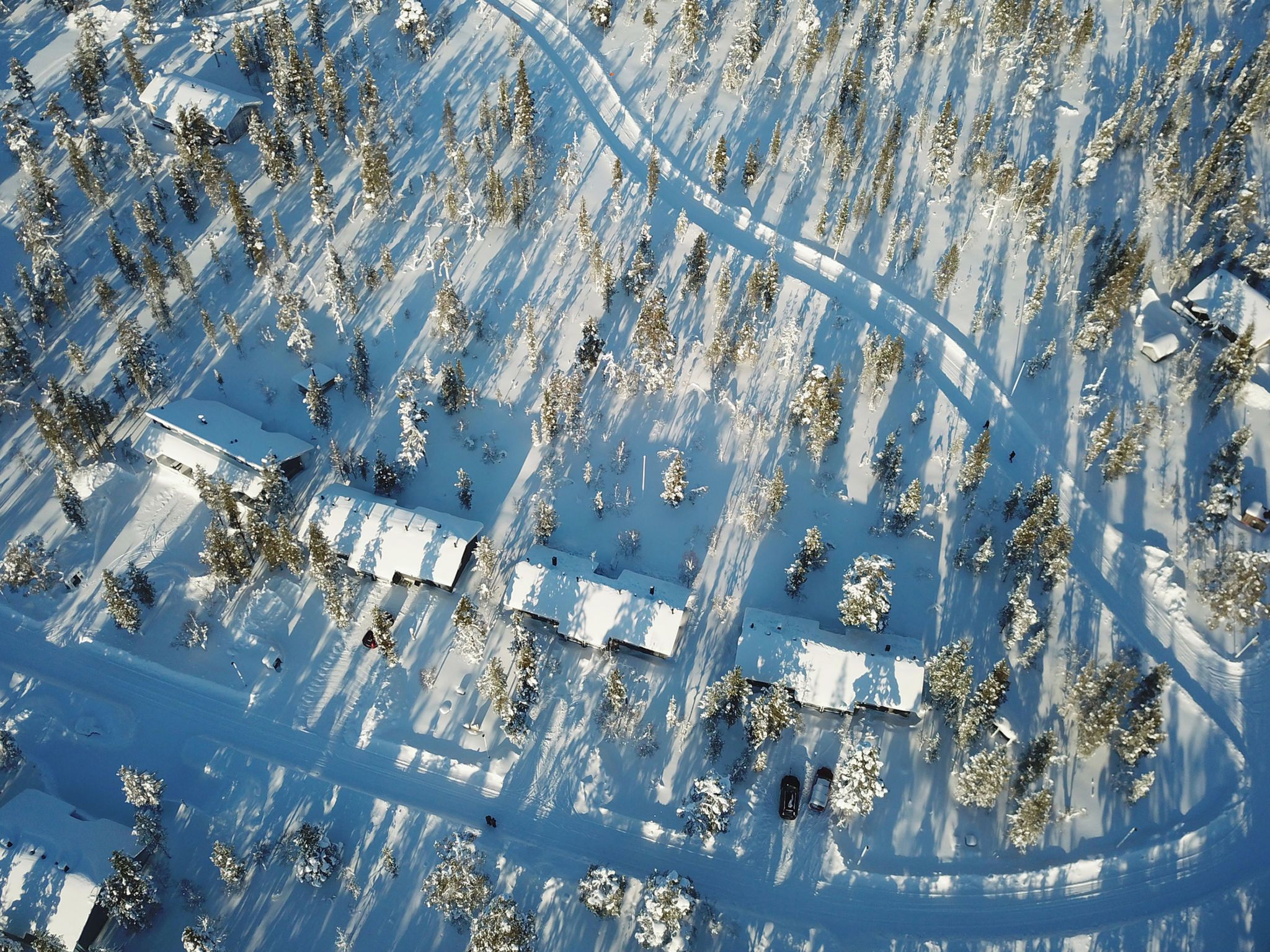 Luchtbeeld van een besneeuwd landschap met verspreide gebouwen en bomen.