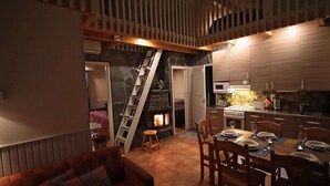 Un espacio habitable acogedor y compacto con comedor, cocina y dormitorio en entrepiso.