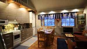 Una cocina moderna con comedor, armarios de madera, horno empotrado y televisor.