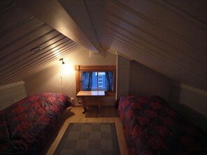 Una habitación tipo dormitorio con dos camas, un escritorio y una ventana con cortinas.