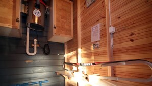 Une cuisine compacte aux murs en bois, dotée d’une cuisinière intégrée et d’un petit évier.