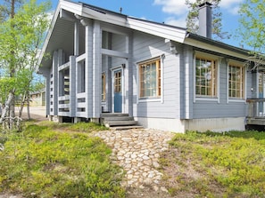 A two-story building with a stone-paved entrance, wooden steps, and a porch with columns.