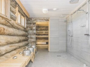 A log cabin interior with a shower, wooden benches, and a built-in bench with storage containers. - Kiilopään maja by Interhome (Inari)