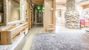 Ein Blockhaus-Interieur mit einer Steinsäule, Holzbanken und einem Teppichboden.