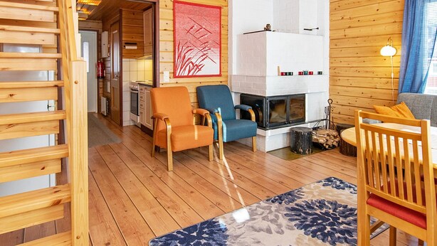 Un intérieur de chalet chaleureux, avec un revêtement en bois, une cheminée et un coin repas.
