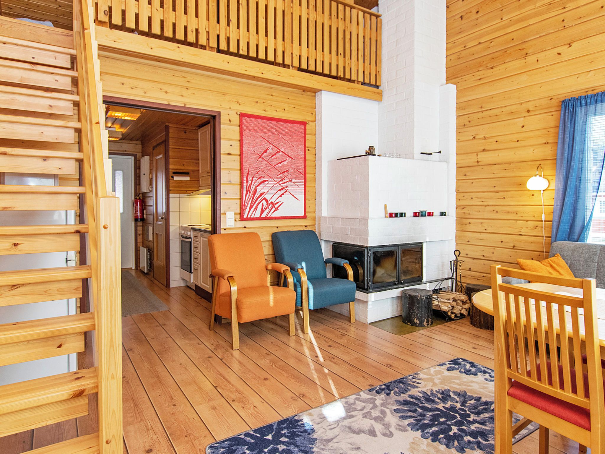 Ein Holzinnenraum mit Kamin, zwei Stühlen, einem Teppich und einer Holztreppe.