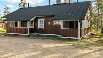 A two-story wooden cabin with a dark roof, a front porch, and a small attached garage.