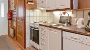 Une cuisine de taille réduite, dotée de meubles blancs, d’une cuisinière, d’un four, d’un évier et d’un lave-vaisselle.