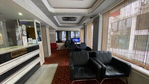 Un'area reception con scrivania, sedute in pelle e televisore.