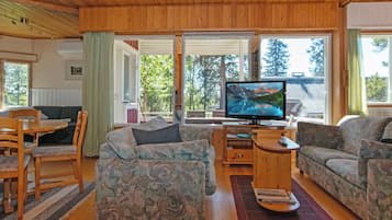 Ein gemütliches Wohnzimmer mit Fernseher, zwei Sofas, einem Couchtisch und einem Essbereich mit Stühlen und einem Tisch.