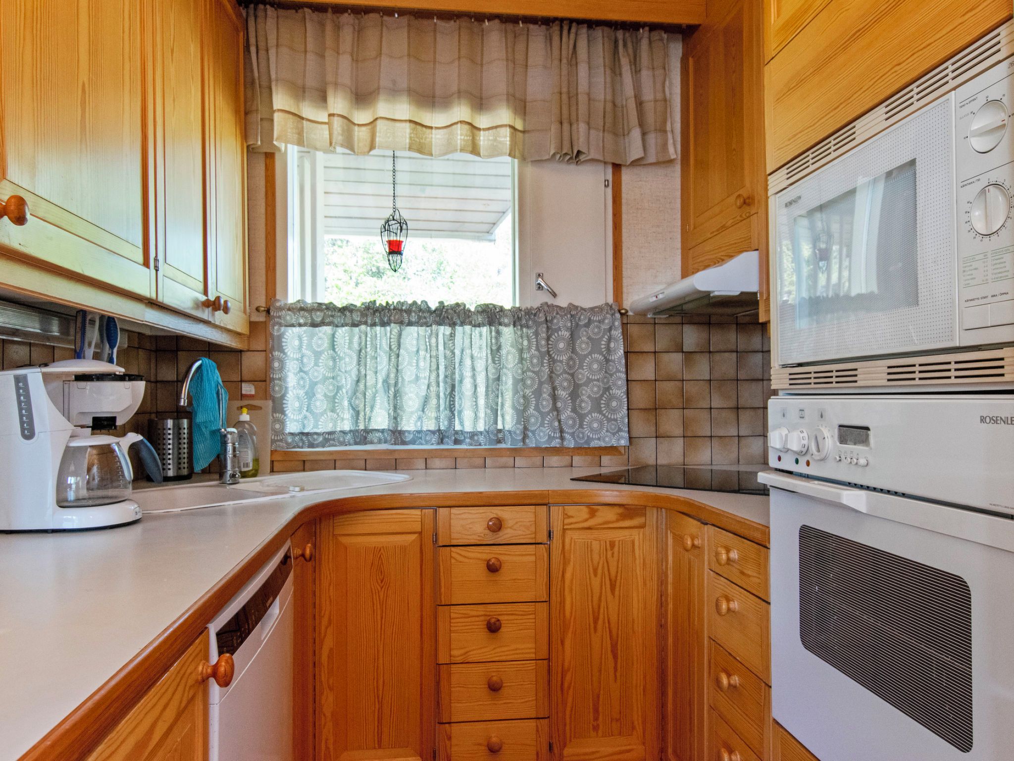 A kitchen with wooden cabinets, a built-in microwave, and a coffee maker.