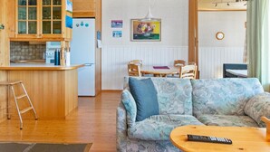 Un accogliente interno di una baita con cucina in legno, zona pranzo e soggiorno.