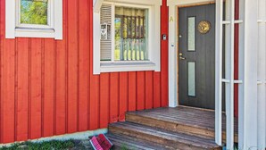 Una casa di legno rossa con una porta scura, finestre con cornice bianca e un piccolo portico con gradini.