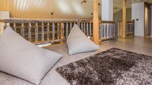 Une pièce spacieuse avec un plafond haut, des poutres en bois et une rambarde rustique.