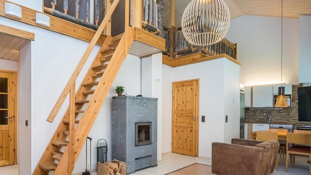 Un vaste espace de vie comprenant un escalier en bois, une cheminée, une cuisine et un coin repas.