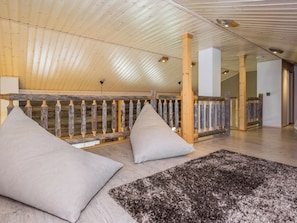 Una habitación con techo y barandilla de madera, y una alfombra grande.