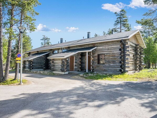 A log cabin with a porch, a chimney, and a sign indicating no parking.