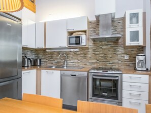 A modern kitchen with a dishwasher, oven, microwave, and a coffee maker.