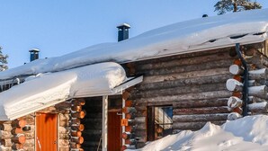 Une cabane en rondins avec un toit enneigé et une porte en bois.