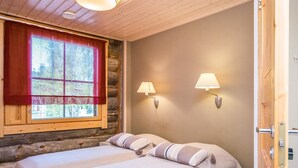 Une pièce confortable avec deux lits, une fenêtre ornée de rideaux rouges et des lampes fixées au mur.