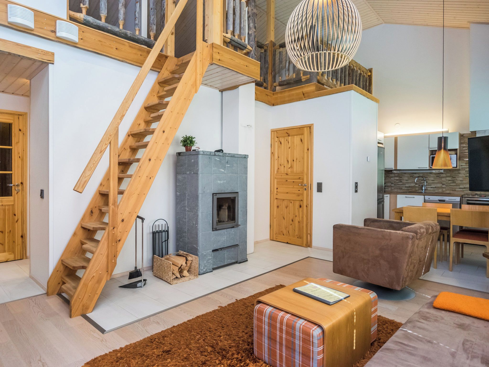 A modern interior with a wooden staircase, a fireplace, a dining area, and a kitchen.