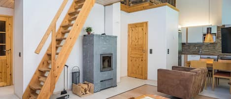 A modern interior with a wooden staircase, a fireplace, a dining area, and a kitchen.
