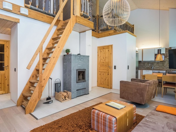 A modern interior with a wooden staircase, a fireplace, a dining area, and a kitchen.