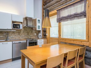 A modern kitchen with a wooden table and chairs, a built-in oven, a microwave, and a coffee maker.
