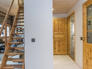 A wooden staircase leading to a lofted area with a view of the outdoors.