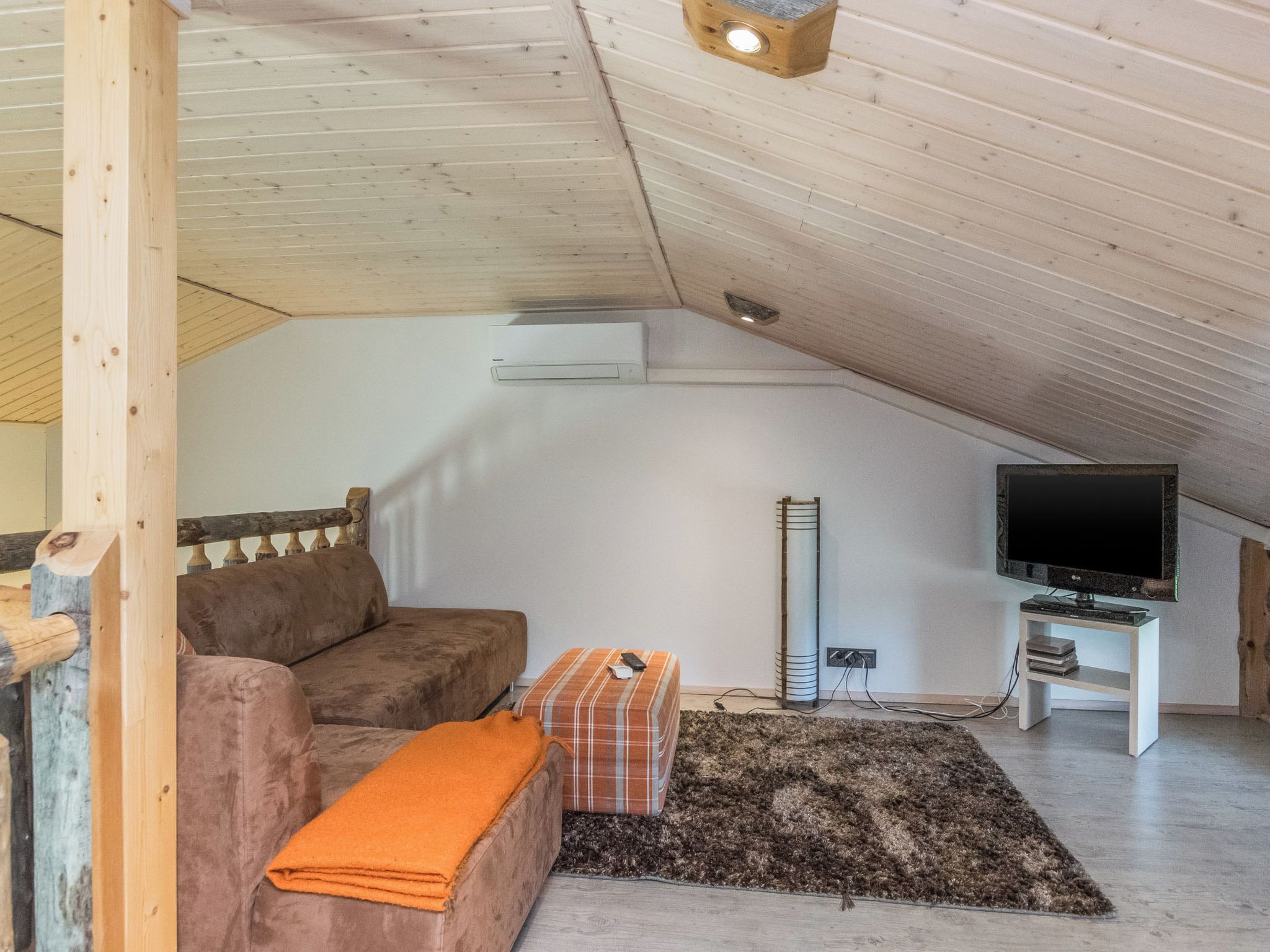 Une chambre mansardée avec un canapé, une petite table, un téléviseur et un radiateur.