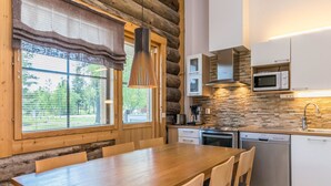Una cocina moderna con una mesa y sillas de madera, un salpicadero de piedra y vistas al exterior.