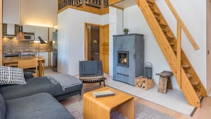 Una sala de estar moderna con chimenea, una escalera de madera y una zona de cocina.