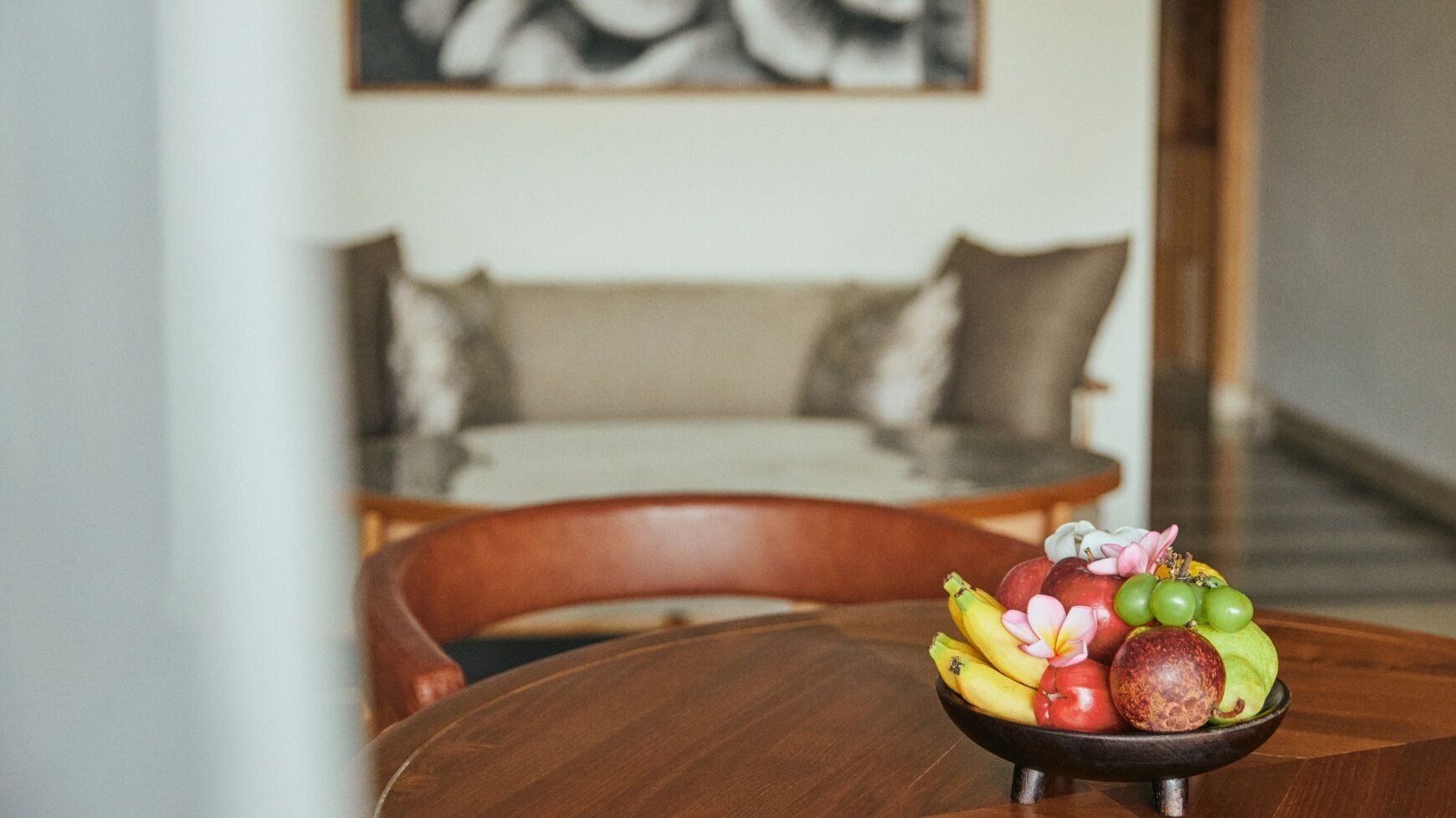 A dining table with a bowl of fruit in the foreground.