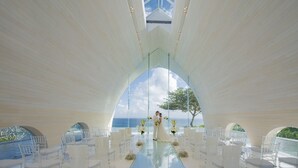An indoor wedding ceremony with a glass floor, white chairs, and a view of the sea. - AYANA Segara Bali (Jimbaran)