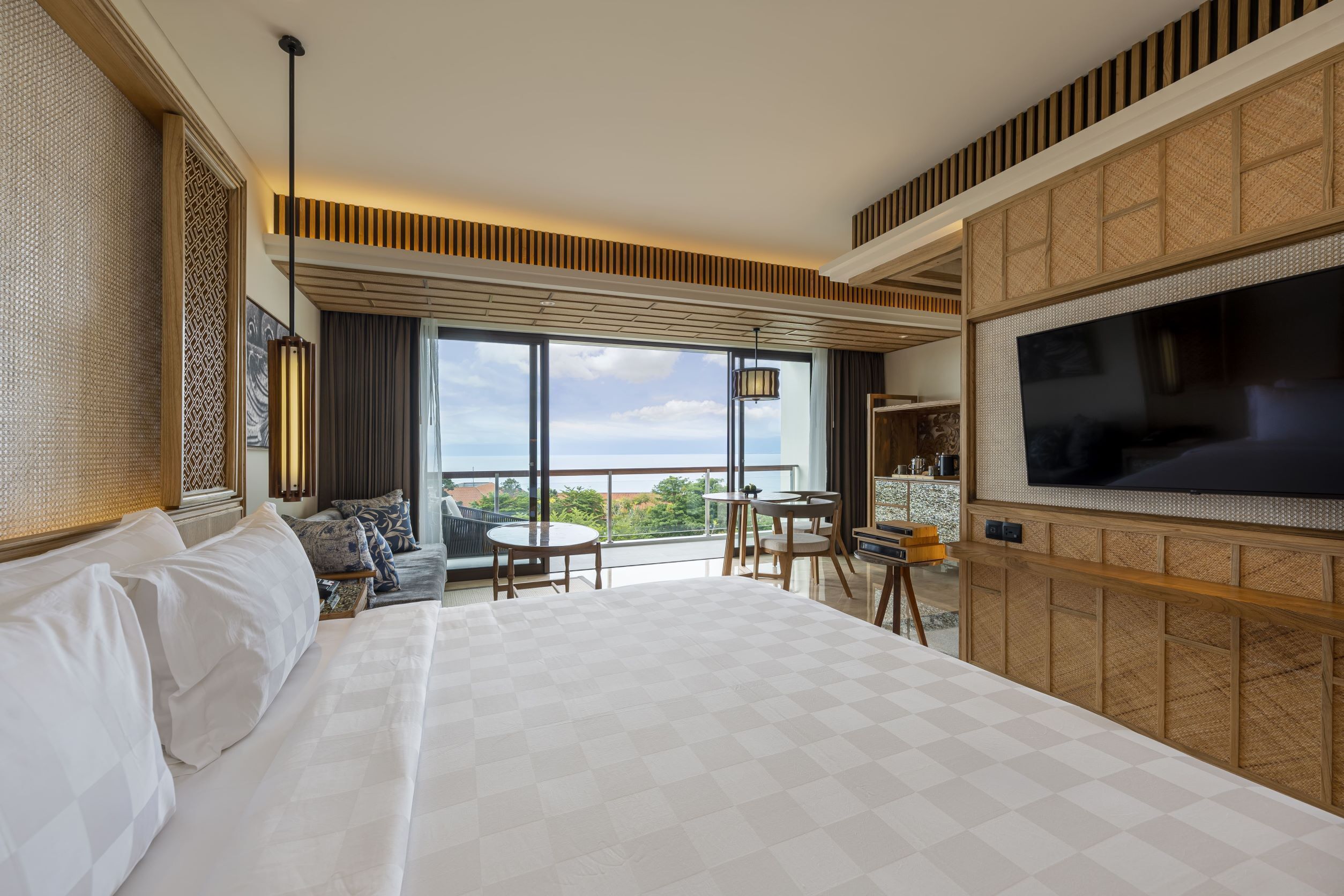Une chambre d’hôtel avec un grand lit, une télévision, un balcon avec vue et un coin repas.