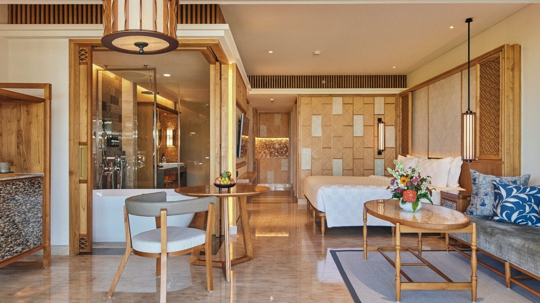 A modern hotel room with a wooden floor, a sofa, a dining table, and a bed.