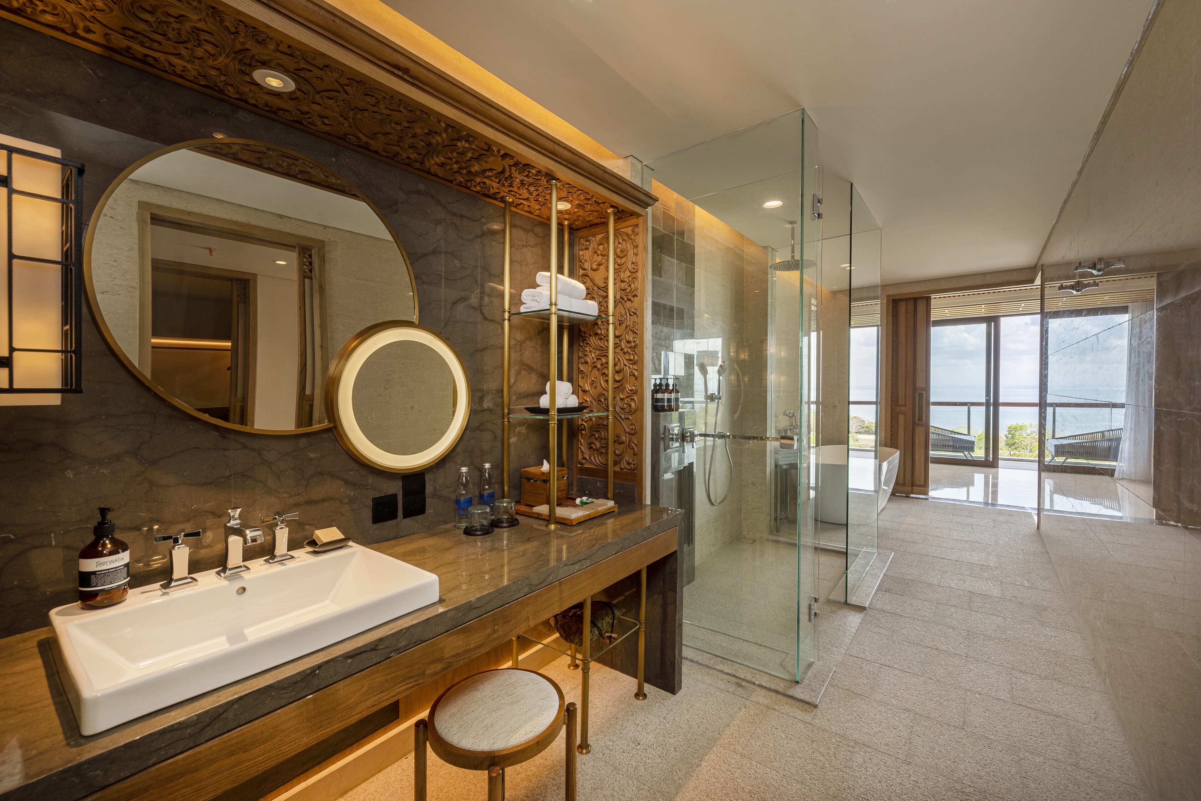 Une salle de bain moderne dotée d’un grand lavabo, de deux miroirs, d’une douche en verre et offrant une vue sur l’extérieur.