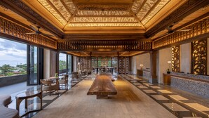 A spacious lobby with a long reception desk, comfortable seating, and large windows offering views of the outdoors. - AYANA Segara Bali (Jimbaran)