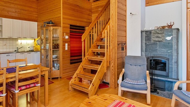A wooden interior with a staircase, a fireplace, and a dining area. - Kuksatie 7 a by Interhome (Inari)