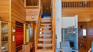 A wooden interior with a spiral staircase, a fireplace, and two rocking chairs. - Kuksatie 7 a by Interhome (Inari)