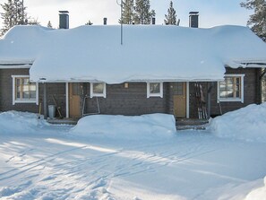 Une maison en bois avec un toit enneigé et un porche à l’avant.