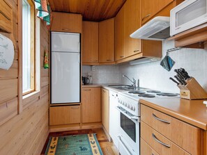 A compact kitchen with wooden cabinets, a white refrigerator, a stove, and a microwave.