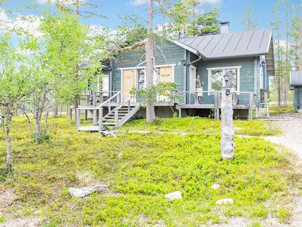 A rustic cabin with a porch, wooden stairs, and a small deck area.
